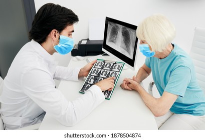 Pulmonologist Wearing A Protective Mask Showing A Senior Patient A CT Scan Of Her Lungs. Pneumonia, Coronavirus, Lung Disease