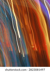 Pulsating trails of light from the carousel, moving in the darkness, almost vertically, from top to bottom.