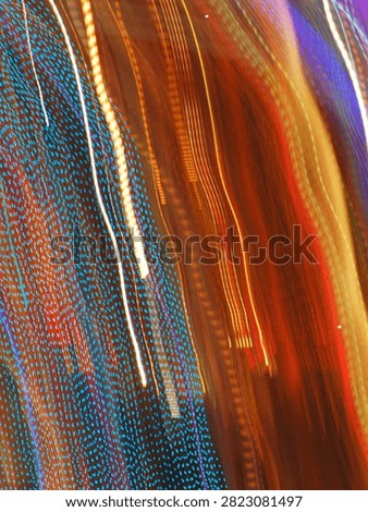 Pulsating trails of light from the carousel, moving in the darkness, almost vertically, from top to bottom.