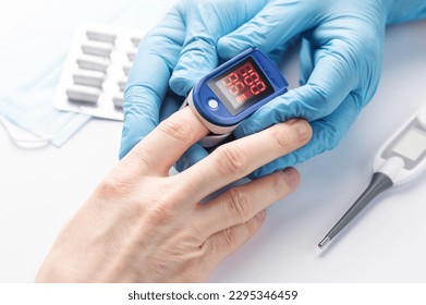 Pulse oximeter measuring oxygen saturation in blood and heart rate.  Pulse oximeter on the patient's hand
