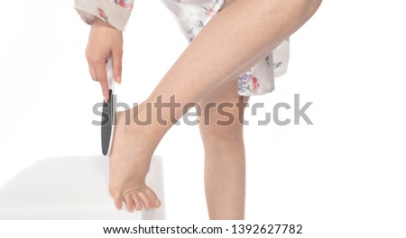Pumice foot file. Young woman removing hard skin on her foot with pumice stone.