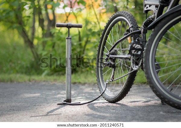A pump and a bicycle. Bicycle repair in the forest.\
Close up.
