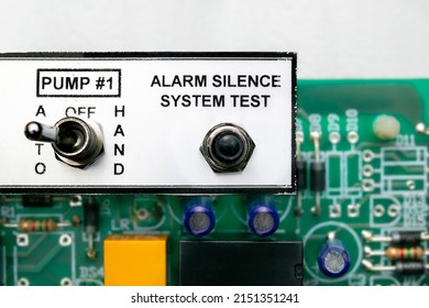Pump  controller or pump system control panel, close up. Used in residential or commercial sump and sewage system. Focus on the alarm silence test switch with defocused motherboard. Selective focus.
