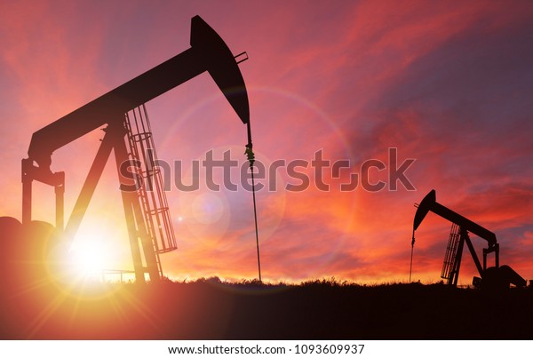 Pump jack\
silhouette against a sunset sky with deliberate lens flare and copy\
space. These jacks can extract between 5 to 40 litres of crude oil\
and water emulsion at each\
stroke.