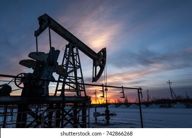 Pump jack at sunset sky background. Extraction of oil. Petroleum concept.