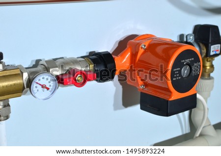 Pump with a thermometer for a water underfloor heating system at home. Sensor and temperature control. Manometer, pipe, flow meter, and valves of heating system in a boiler room. 