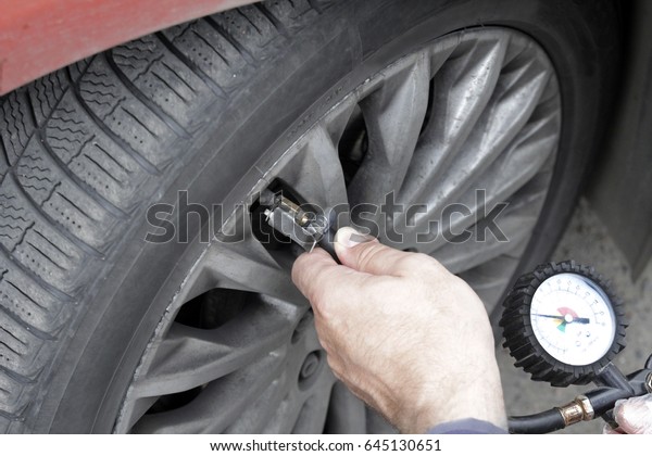 Pumping car tires in the service station.\
People at work. The man inflates car\
tires