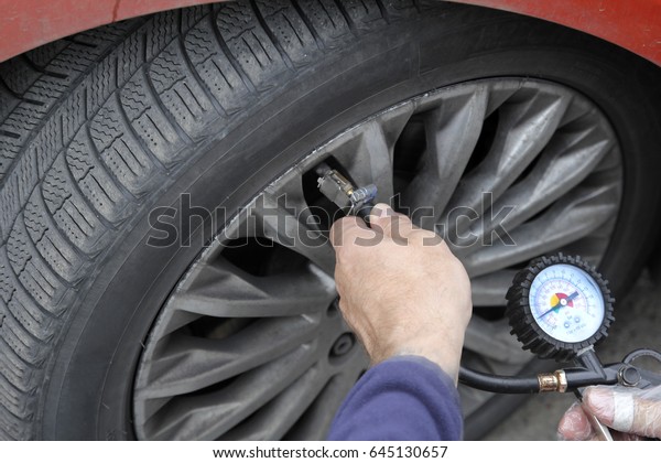 Pumping car tires in the service station.\
People at work. The man inflates car\
tires