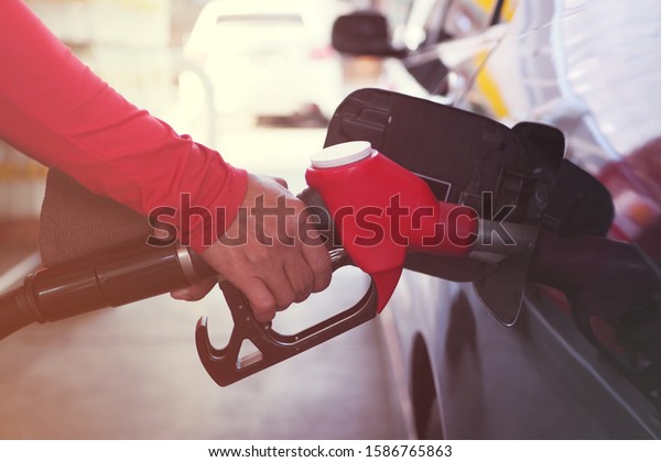Pumping gas at petrol\
station. Man pumping gasoline fuel in car at gas station. Good\
service by man