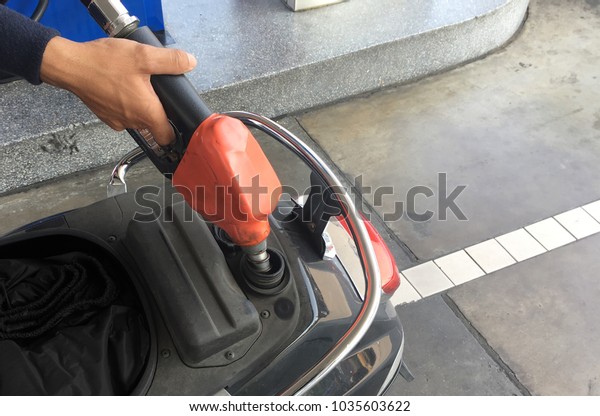 Pumping gas at gas pump. Closeup of man\
pumping gasoline fuel in motorcycle at gas\
station.