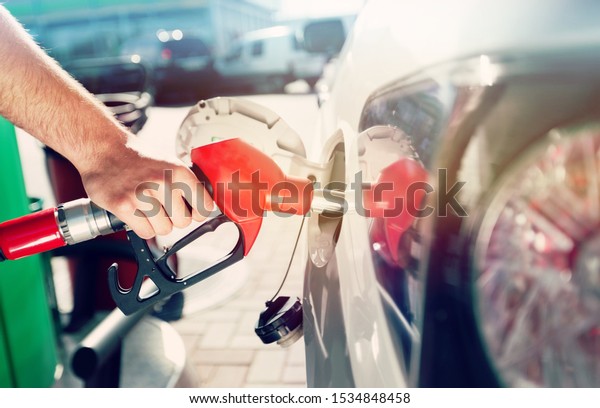 Pumping\
gas at gas pump. Closeup of man pumping gasoline fuel in car at gas\
station. Man\'s hand refueling car at gas\
station