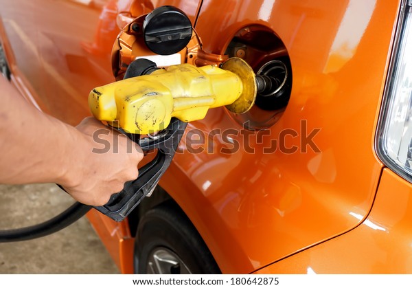 Pumping gas at gas pump. Closeup of man\
hand pumping gasoline fuel in car at gas station.\
