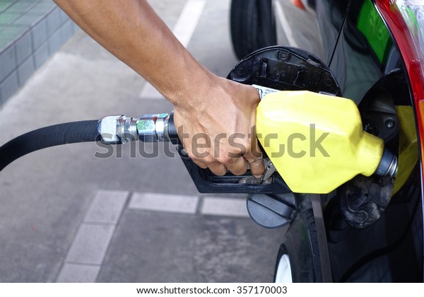 Pumping gas at gas pump. Closeup\
of man pumping gasoline fuel in car at gas station              \
