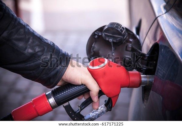 Pumping gas at gas pump. Closeup of man\
hand pumping gasoline fuel in car at gas\
station.