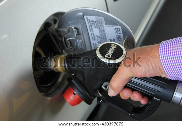 Pumping gas at a self service gas station (Diesel\
is a type of fuel)