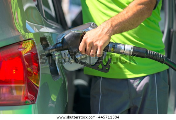 Pumping gas at gas station. Close up of a hand\
holding fuel nozzle.