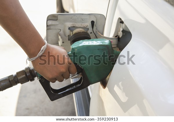 Pumping gasoline fuel in a car at\
gas station, Closeup of hand holding Pumping gasoline\
fuel