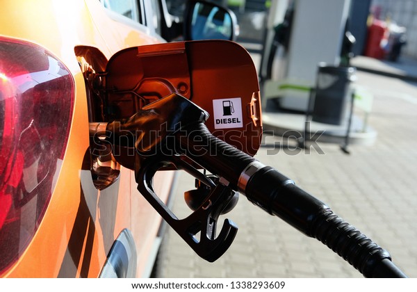 Pumping\
gasoline fuel in orange car at a gas station. To fill car with fuel\
in petrol station. Diesel inscription. Close\
up.