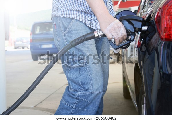 Pumping petrol at gas pump. Closeup of\
man pumping gasoline fuel in blue car at gas\
station