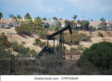 A pumpjack derrick drilling for oil in Los Angeles, next to a residential area