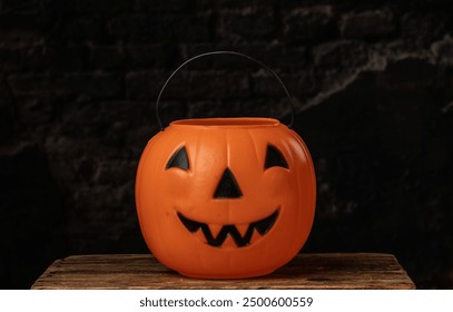 Pumpkin bucket for trick or treating on a wooden box in front of a weathered brick background - Powered by Shutterstock