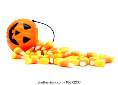 Pumpkin candy holder with spilling Halloween candy corn over white - Powered by Shutterstock