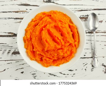 Pumpkin Carrot Baby Puree In Bowl On White Wood Background, Top View. Fresh Orange Squash Vegetable Pumpkin Carrot Puree Or Baby Mash Food In Bowl. Pumpkin Carrot Fruit Smoothie Of Yellow Food In Bowl