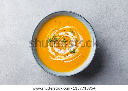 Pumpkin and carrot soup with cream on grey stone background. Close up. Top view. ストックフォト © 