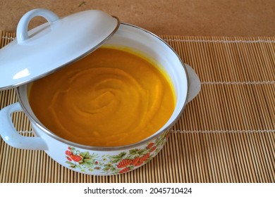 Pumpkin And Carrot Soup In White Pot On Wooden Background