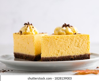 Pumpkin cheesecake with chocolate base layer and cream frosting. Autumn squash dessert. Piece of orange and brown cheesecake with chocolate sprinkles on ceramic plate. Close up view. Fall sweets. - Powered by Shutterstock