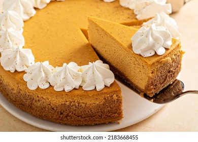 Pumpkin Cheesecake With Fall Spices Topped With Whipped Cream, Dessert For Thanksgiving, Whole Cake With Two Slices Cut