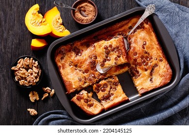 Pumpkin Chocolate Chips Sheet Cake In A Baking Dish With Raw Pumpkin Slices,cinnamon And Walnuts On Dark Wood Table, Horizontal View From Above, Flat Lay, Close-up