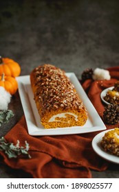 Pumpkin Cream Cheese Cake Roll With Fall Props In The Background.