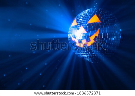 pumpkin disco ball at Halloween party, jack o'lantern with shiny blue rays in smoke