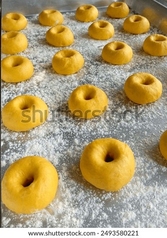 Pumpkin donuts on a baking sheet in the proofing process