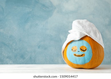 Pumpkin with facial mask and towel on wooden background, copy space