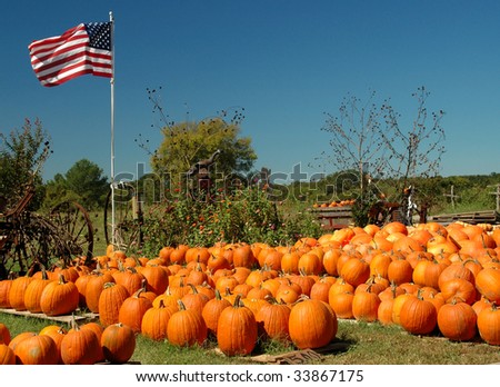 A pumpkin farm with a collection of harvested pumpkins, decorated with scarecrows, wagons and an American flag waving in the wind, vivid colors, horizontal with copy space