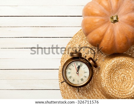 Pumpkin and hat with leafs on white wooden table