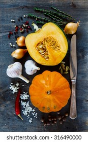 Pumpkin and ingredients for cooking over dark wooden background. Vegetarian food, health or cooking concept.