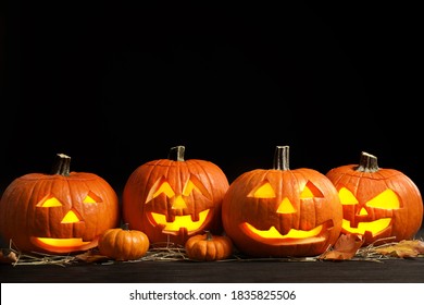 Pumpkin jack o'lanterns on table in darkness, space for text. Halloween decor