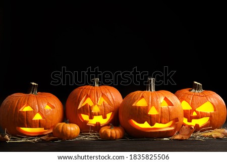 Pumpkin jack o'lanterns on table in darkness, space for text. Halloween decor