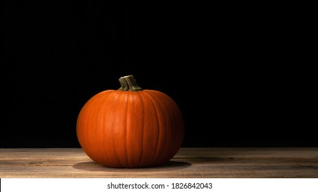 Pumpkin on old dark rustic wooden table. Halloween background with pumpkin. 