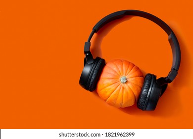 pumpkin on an orange background. wireless headphones on the pumpkin. preparing for halloween