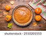 Pumpkin pie on gray wooden desk. Homemade pie. ThanFresh made pumpkin pie in pie mold at rustic table with decorative pumpkin, no people thanksgiving dinner. Autumn.