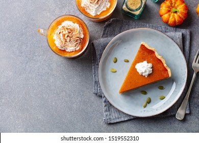 Pumpkin pie on a plate, pumpkin latte with whipped cream. Grey background. Copy space. Top view.