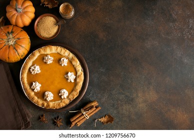 Pumpkin Pie with whipped cream and cinnamon on rustic background, top view. Homemade pastry for Thanksgiving traditional Pumpkin Pie.