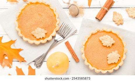 Pumpkin pies, leaf-shaped cookies, fall leaves, cinnamon sticks, figs, silver fork, autumnal decor, warm-toned pie crust, Thanksgiving dessert, cozy holiday table setting - Powered by Shutterstock