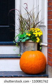 Pumpkin And Potted Plants Outside The Front Door To Celebrate Halloween And The Autumn Season.