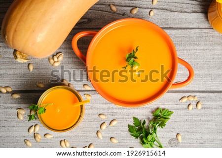 Pumpkin puree with a decorative pumpkin smoothie photographed from above, on a gray rustic table, with its pipes and herbs to complement