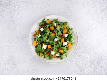 Pumpkin salad with arugula, feta cheese and pomegranate seeds on a gray background. Top view. Thanksgiving Dishes. - Powered by Shutterstock